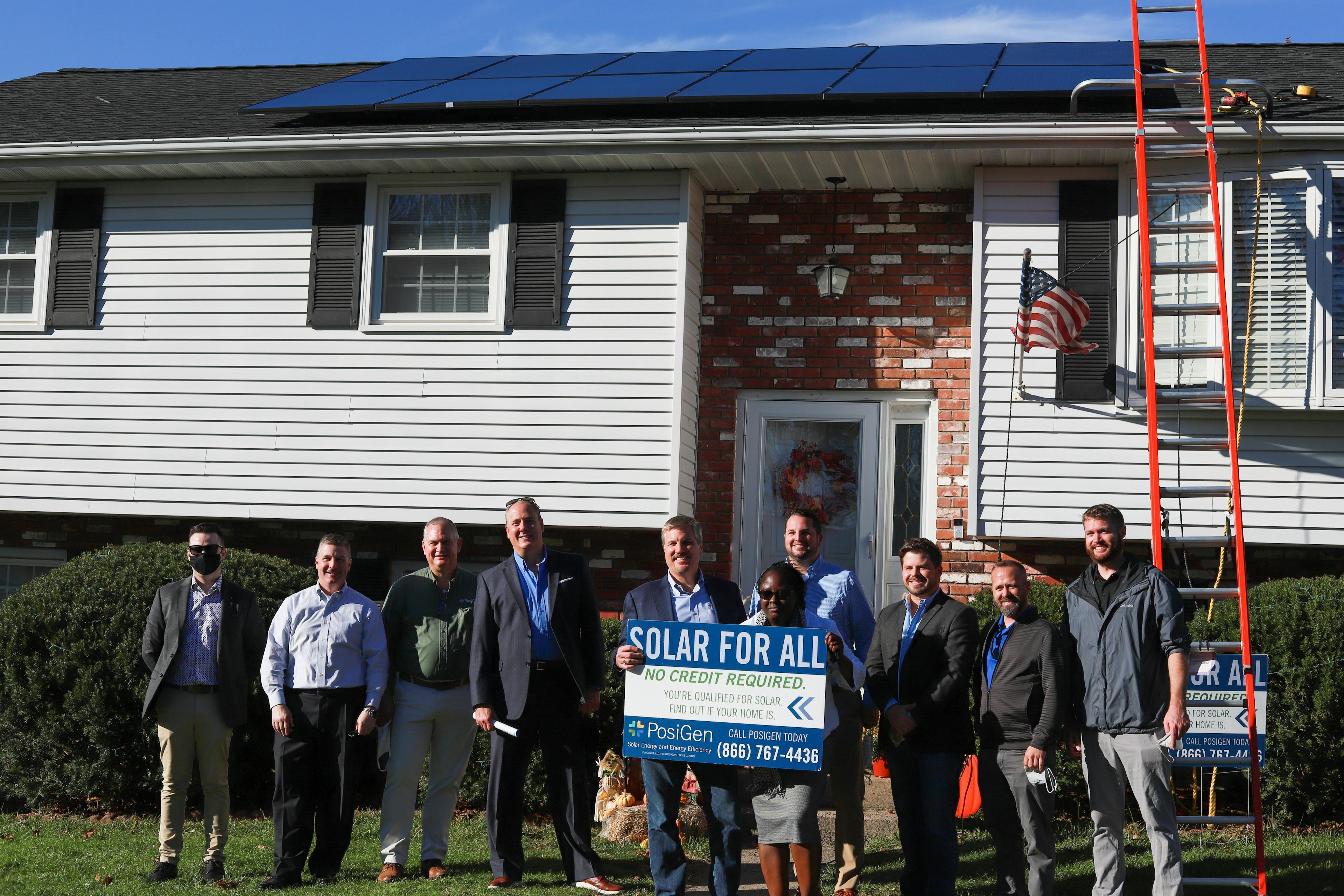 PosiGen CEO Tom Neyhart and various members of the PosiGen team with a homeowner who just had solar installed on her home.